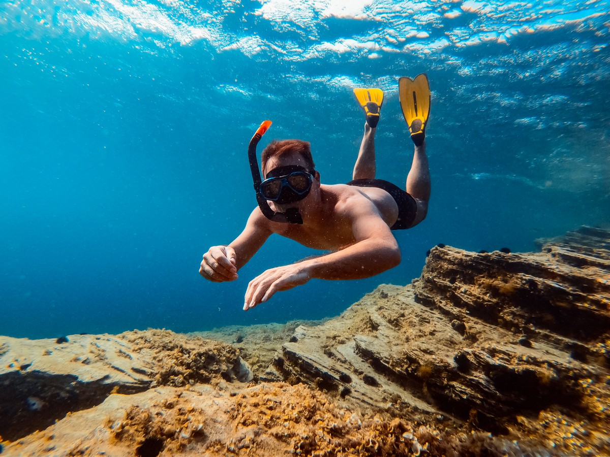 Underwater photo of men snorkeling in the sea water Underwater photo of men snorkeling in the sea water